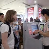 Nhân viên an ninh hàng không kiểm tra giấy tờ hành khách trước khi vào khu vực soi chiếu. (Ảnh: Huy Hùng/TTXVN)