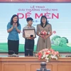 Phó Tổng giám đốc Thông tấn xã Việt Nam Nguyễn Thị Sự (trái) trao giải Khát vọng Dế Mèn cho tác giả Lê Sinh Hùng (giữa). (Ảnh: Minh Quyết/TTXVN)