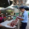 Lực lượng Quản lý thị trường tỉnh Lạng Sơn tuyên truyền, ký cam kết với hộ kinh doanh tại chợ Trung tâm thương mại thị trấn Đồng Đăng, huyện Cao Lộc. (Ảnh: PV/Vietnam+)