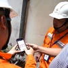 Nhân viên EVNHANOI hướng dẫn khách hàng kiểm tra hóa đơn điện ngay trên App EVNHANOI. (Ảnh: evnhanoi)