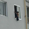 Nam thanh niên trèo lên cửa sổ, ném gạch đá xuống gây nguy hiểm cho cư dân tòa nhà Packexim. (Ảnh: otofun)