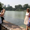 Du khách chụp ảnh bên hồ Hoàn Kiếm. (Ảnh: Trần Việt/TTXVN)