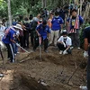 Lực lượng chức năng khai quật thi thể các nạn nhân trong ngôi mộ tập thể ở Thái Lan. (Nguồn: AFP/TTXVN)