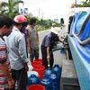 Người dân Rạch Giá phải sử dụng mọi vật dụng hiện có để lấy nước tại các xe bồn cấp nước. (Ảnh: Trường Giang/TTXVN)