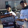 Thân nhân hành khách người Malaysia và Trung Quốc nắm tay nhau tổ chức hoạt động tưởng niệm một năm ngày MH370 mất tích. (Nguồn: QQ)