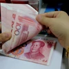 Kiểm tiền giấy mệnh giá 100 nhân dân tệ tại ngân hàng ở Liên vận cảng, tỉnh Giang Tô, Trung Quốc ngày 11/8. (Nguồn: AFP/TTXVN)