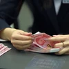 Nhân viên ngân hàng kiểm tiền 100 nhân dân tệ mới tại một ngân hàng ở thủ đô Bắc Kinh ngày 12/11. (Nguồn: THX/TTXVN)