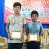 Hai em Bo Tý (trái) và Cao Lâm nhận Huy hiệu “Tuổi trẻ dũng cảm.” (Ảnh: Nguyên Lý/TTXVN)