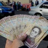 Kiểm tiền mệnh giá 100 Bolivar tại ngân hàng ở Caracas ngày 13/12. (Nguồn: EPA/TTXVN)