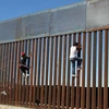 Hai cậu bé cố gắng trèo qua bức tường biên giới giữa Mỹ và Mexico tại Ciudad Juarez, Mexico ngày 26/1. (Nguồn: AFP/TTXVN)