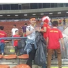 Cổ động viên Việt Nam tự giác và vui vẻ thu dọn rác sau trận đấu. (Ảnh: Hoàng Nhương/Vietnam+)