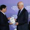 Giáo sư Klaus Schwab, Người sáng lập, Chủ tịch Điều hành Diễn đàn Kinh tế thế giới (bên phải) trao sách tặng Thứ trưởng Thường trực Bộ Ngoại giao Bùi Thanh Sơn. (Ảnh: Lâm Khánh/TTXVN) 