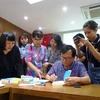 Nhà văn Nguyễn Nhật Ánh tặng chữ ký cho độc giả. (Ảnh: Gia Thuận/TTXVN) 
