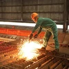 Công nhân Nhà máy cán thép Thái Trung, Công ty Cổ phần gang thép Thái Nguyên lấy mẫu thép cán mới ra lò. (Ảnh: Hoàng Nguyên/TTXVN) 