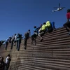 Người di cư vượt qua bức tường biên giới Mỹ-Mexico ở gần cửa khẩu El Chaparral, Tijuana, bang Baja California, Mexico ngày 25/11/2018. (Nguồn: AFP/TTXVN) 