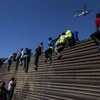 Người di cư trèo qua hàng rào ngăn cách biên giới Mỹ-Mexico gần cửa khẩu El Chaparral ở Tijuana, bang Baja California, Mexico, ngày 25/11/2018. (Nguồn: AFP/TTXVN) 