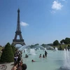 Người dân tránh nắng nóng bên vòi phun nước ở Paris, Pháp, ngày 26/6/2019. (Nguồn: THX/TTXVN) 
