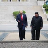 Tổng thống Mỹ Donald Trump (trái) và nhà lãnh đạo Triều Tiên Kim Jong-un bước chân qua đường ranh giới phân chia hai miền Triều Tiên tại DMZ, sang phần lãnh thổ của Triều Tiên chiều 30/6/2019. (Ảnh: AFP/TTXVN)