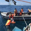Lực lượng cứu hộ di chuyển các vật dụng thiết yếu trên tàu cá BĐ 99137 TS xuống xuồng cứu nạn. (Ảnh: Huỳnh Ngọc Sơn/TTXVN) 