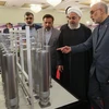 Người đứng đầu Tổ chức Năng lượng nguyên tử Iran (AEOI) Ali Akbar Salehi (phải) báo cáo với Tổng thống Iran Hassan Rouhani (thứ 2, trái) thăm quan một triển lãm nhân Ngày công nghệ hạt nhân ở Tehran. (Nguồn: AFP/TTXVN) 