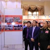 Thượng tướng Thongloy Silivong, Thứ trưởng, Chủ nhiệm Tổng cục Chính trị Bộ Quốc phòng Lào và Đại sứ Việt Nam tại Lào Nguyễn Bá Hùng cùng các quan khách tham quan Triển lãm. (Ảnh: Phạm Kiên/TTXVN) 
