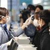 Nhân viên hàng không kiểm tra thân nhiệt các hành khách trước khi họ về Vũ Hán (Trung Quốc) tại sân bay quốc tế thủ đô Tokyo, Nhật Bản ngày 31/1/2020. (Nguồn: THX/TTXVN) 