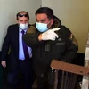Bộ trưởng Y tế Bolivia Marcelo Navajas (trái) được áp giải tới phiên điều trần ở La Paz do liên quan tới bê bối mua máy trợ thở, ngày 20/5/2020. (Nguồn: AFP/TTXVN) 
