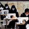 Phụ nữ may khẩu trang và đồ bảo hộ chống dịch COVD-19 tại Tehran, Iran. (Ảnh: AFP/TTXVN) 