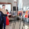 Thiếu tá Chuck Casey, Tùy viên Thủy quân Lục chiến Hoa Kỳ tại Việt Nam và ông Võ Văn Hưng, Chủ tịch UBND tỉnh Quảng Trị xem triển lãm. (Ảnh: Hồ Cầu/TTXVN) 