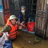 Lực lượng công an huyện Lệ Thủy lội nước, đưa hàng cứu trợ đến những gia đình bị cô lập trong nước lũ. (Ảnh: Thành Đạt/TTXVN) 