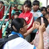 Các em học sinh nhóm thiện nguyện Fly to Sky chải tóc cho trẻ em làng Đê Kôn. (Ảnh: Hồng Điệp/TTXVN) 