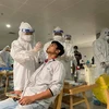 Nhân viên y tế lấy mẫu xét nghiệm cho người làm việc tại sân bay Tân Sơn Nhất ngày 6/2. (Nguồn: TTXVN phát) 