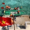 Cờ Tổ quốc tung bay phấp phới khi hai xuồng của tàu Trường Sa 571 cập mạn trên đảo Cô Lin. (Ảnh: Sỹ Tuyên/TTXVN) 