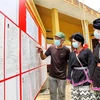 Cử tri bản người Dao ở Khu Dáy, xã Thu Cúc, huyện Tân Sơn, tỉnh Phú Thọ xem danh sách cử tri được niêm yết tại nhà văn hoá bản. (Ảnh: Trung Kiên/TTXVN) 