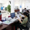 Cán bộ công chức Trung tâm Phục vụ hành chính công tỉnh Ninh Thuận giải quyết hồ sơ, thủ tục hành chính cho các doanh nghiệp. (Ảnh: Công Thử/TTXVN) 