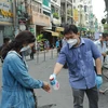 Người dân xịt tay sát khuẩn trước khi vào khu vực mua sắm của 'Phiên chợ lưu động' được tổ chức tại khu phố 3, phường 2, Quận 3, Thành phố Hồ Chí Minh. (Ảnh: Quang Châu/TTXVN) 
