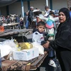 Người dân Palestine nhận hàng cứu trợ tại Dải Gaza. (Ảnh: AFP/TTXVN) 
