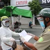 Một người phụ nữ đi chợ trình giấy có giấy tiêm đủ vaccine cho lực lượng kiểm tra trên đường Yersin, thành phố Thủ Dầu Một. (Ảnh: Chí Tưởng/TTXVN) 