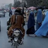 Một nhóm phụ nữ băng qua đường khi các thành viên của Taliban lái xe qua Kabul, Afghanistan. (Nguồn: Reuters) 
