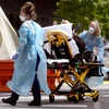 Nhân viên y tế chuyển bệnh nhân COVID-19 tới bệnh viện tại Melbourne, Australia. (Ảnh: AFP/TTXVN) 