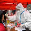 Nhân viên y tế lấy mẫu xét nghiệm COVID-19 cho người dân tại Thanh Đảo, tỉnh Sơn Đông, Trung Quốc, ngày 13/3/2022. (Ảnh: THX/TTXVN) 