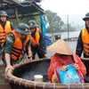 Lực lượng chức năng hỗ trợ người dân ứng phó với mưa lũ. (Ảnh: TTXVN phát) 