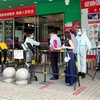 Người dân xếp hàng để kiểm tra thông tin trước khi vào siêu thị tại Thâm Quyến, Trung Quốc. (Ảnh: AFP/TTXVN) 