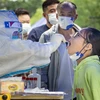 Nhân viên y tế lấy mẫu xét nghiệm COVID-19 cho người dân tại Tứ Xuyên, Trung Quốc. (Ảnh: AFP/TTXVN)