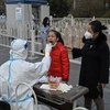 Nhân viên y tế lấy mẫu xét nghiệm COVID-19 cho người dân tại Bắc Kinh, Trung Quốc, ngày 22/11/2022. (Ảnh: AFP/TTXVN) 