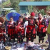 Phụ nữ dân tộc Mông thích thú khi lựa chọn, thử trang phục tại chợ phiên Phìn Hồ. (Ảnh: Xuân Tiến/TTXVN)