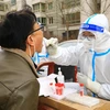 Nhân viên y tế lấy mẫu xét nghiệm COVID-19 cho người dân tại Trung Quốc, ngày 24/11/2022. (Ảnh: AFP/TTXVN)