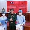 Thiếu tướng, Phó Giáo sư, Tiến sỹ Nguyễn Xuân Kiên, Giám đốc Bệnh viện 103 Việt Nam, tặng quà cho 2 bệnh nhân người Lào được ghép thận thành công. (Ảnh: Phạm Kiên-Bá Thành/TTXVN)