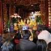 Người dân lễ phật A di đà bằng đá là một trong những bảo vật quốc gia tại chùa Phật Tích. (Ảnh: Thanh Thương/TTXVN)