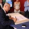 Đại sứ Vũ Quang Minh ghi sổ lưu niệm của thành phố Bühl. (Ảnh: Vũ Tùng/TTXVN)